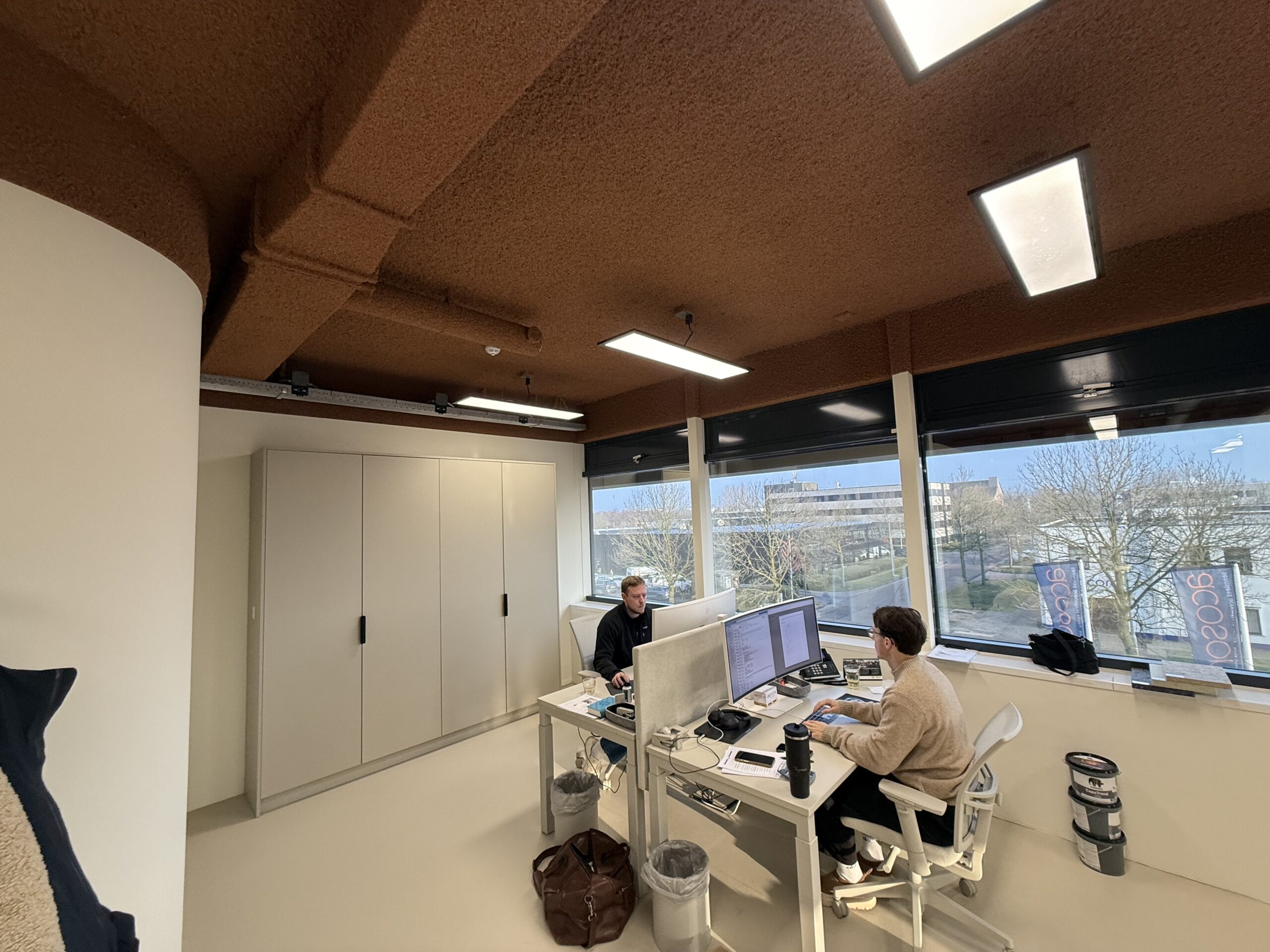 Open space avec plafond acoustique projeté brun et dalles lumineuses encastrées
