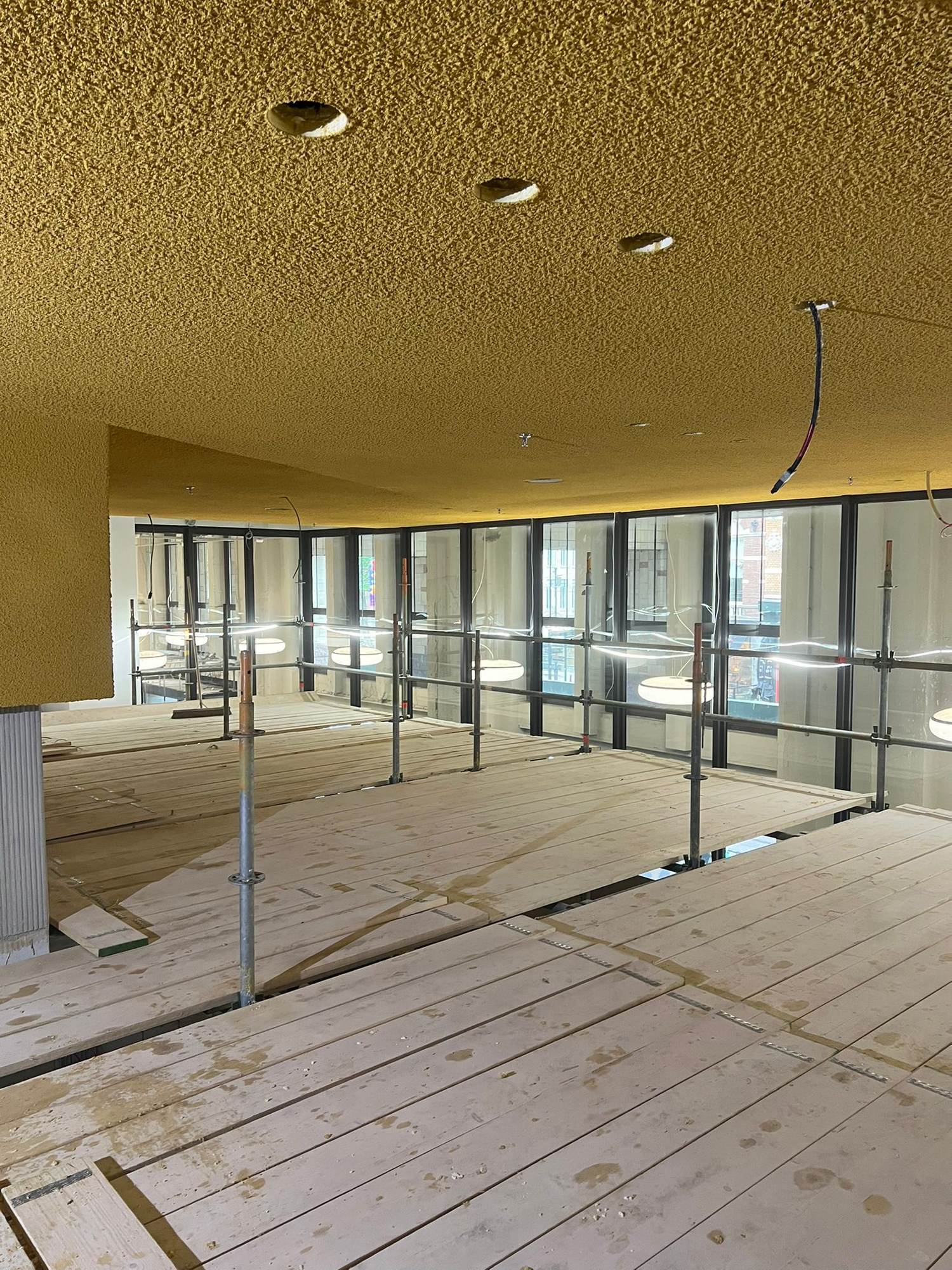 Plafond et retombée en projection acoustique teintée jaune moutarde avec réservations de spots percées après projection, deux postes de surcoût sur devis