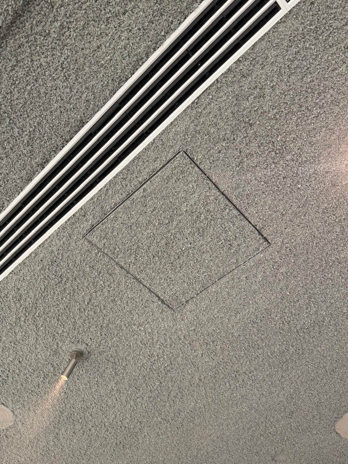 Trappe de visite et diffuseur linéaire de ventilation intégrés dans l'épaisseur d'un plafond acoustique projeté gris