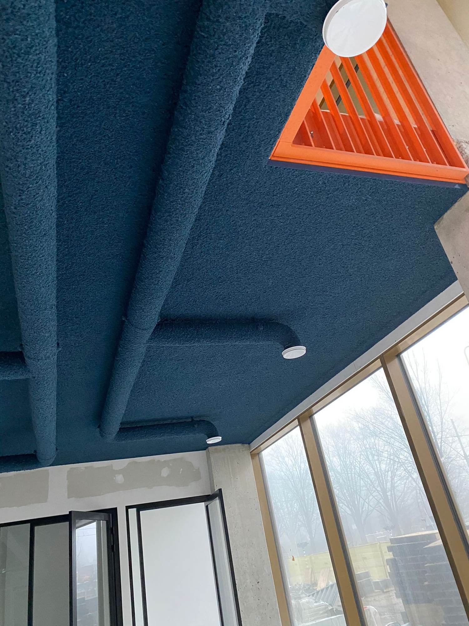 Poutres et sous-face béton nervurées traitées en projection acoustique bleu pétrole, surface développée supérieure à la surface au sol